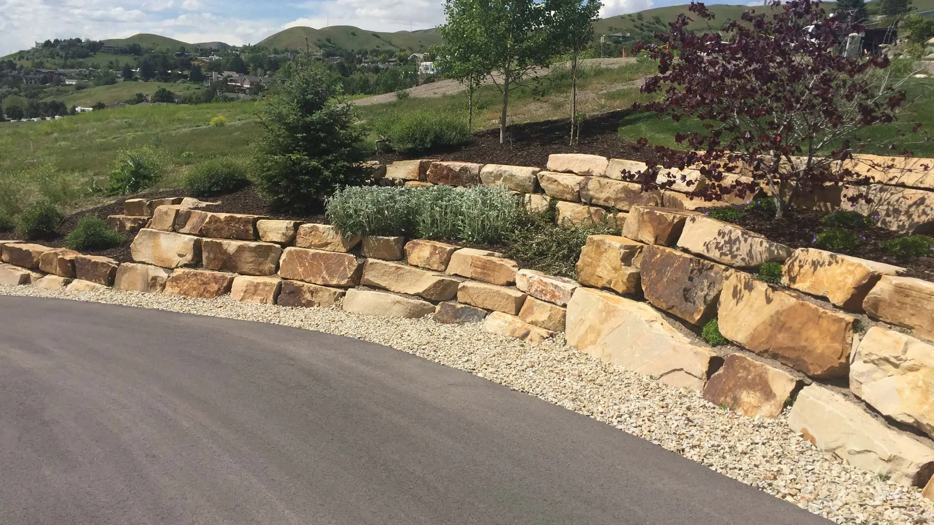 Boulder retaining wall with new mulch and landscaping.