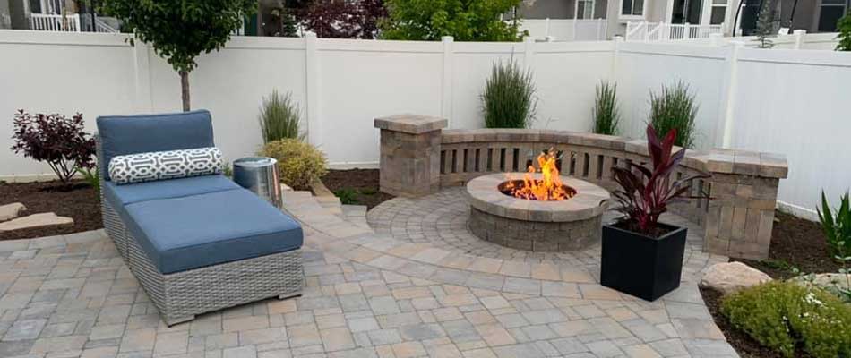 Round fire pit, with a new paver patio, and landscaping in the backyard of a home in Ogden.