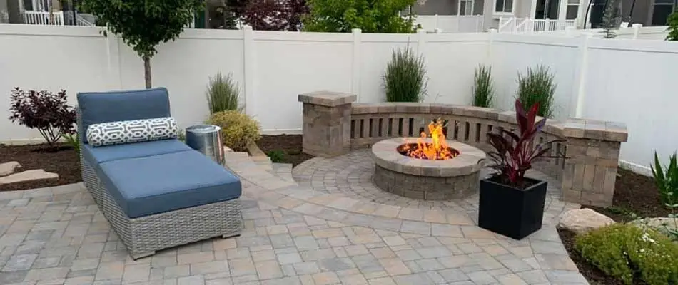 Round fire pit, with a new paver patio, and landscaping in the backyard of a home in Ogden.